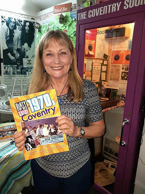 Smiling woman holding a book called The Dirty Stop Puts Guide to 1970s Coventry