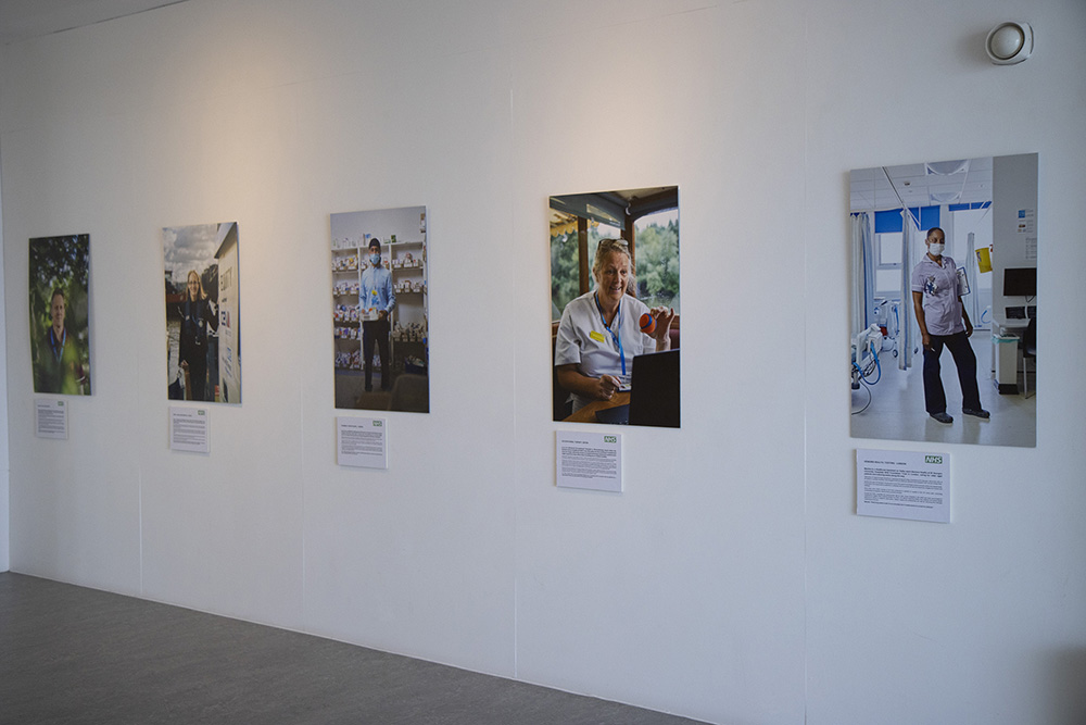 Five photo portraits of NHS staff leading green initiatives hang on the wall of the Herbert Art Gallery