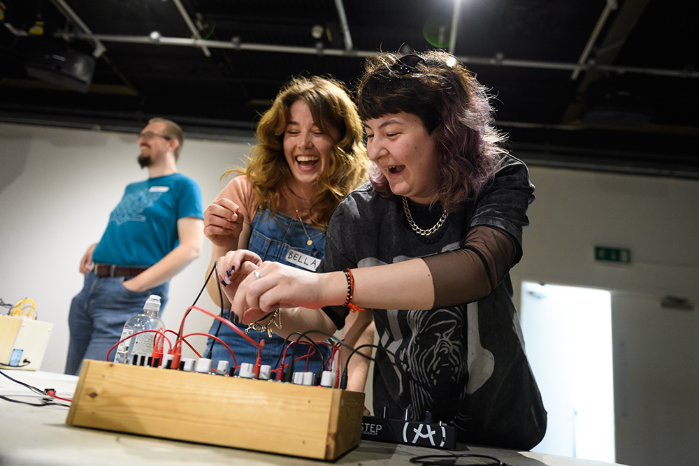 Two laughing women using a modular synthesizer
