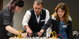 Rick Holt from Frequency Central leading a modular masterclass, with two women trying out modular synths on either side of him