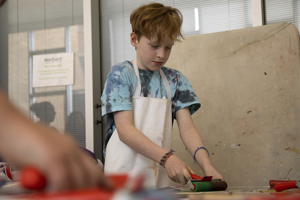 A boy rolling out paint onto a surface for printing