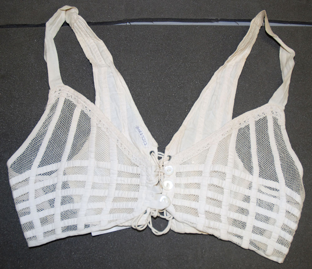 A white 1920s bra with a lace-up back and a mesh front with button fastenings