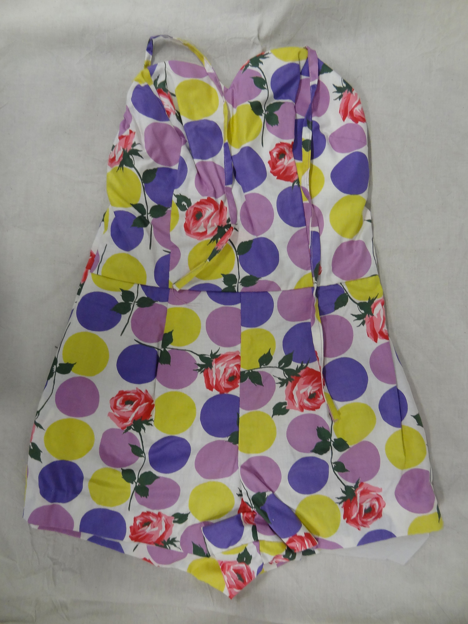 A 1950s women's bathing suit with a printed pattern featuring purple and yellow spots and pink roses