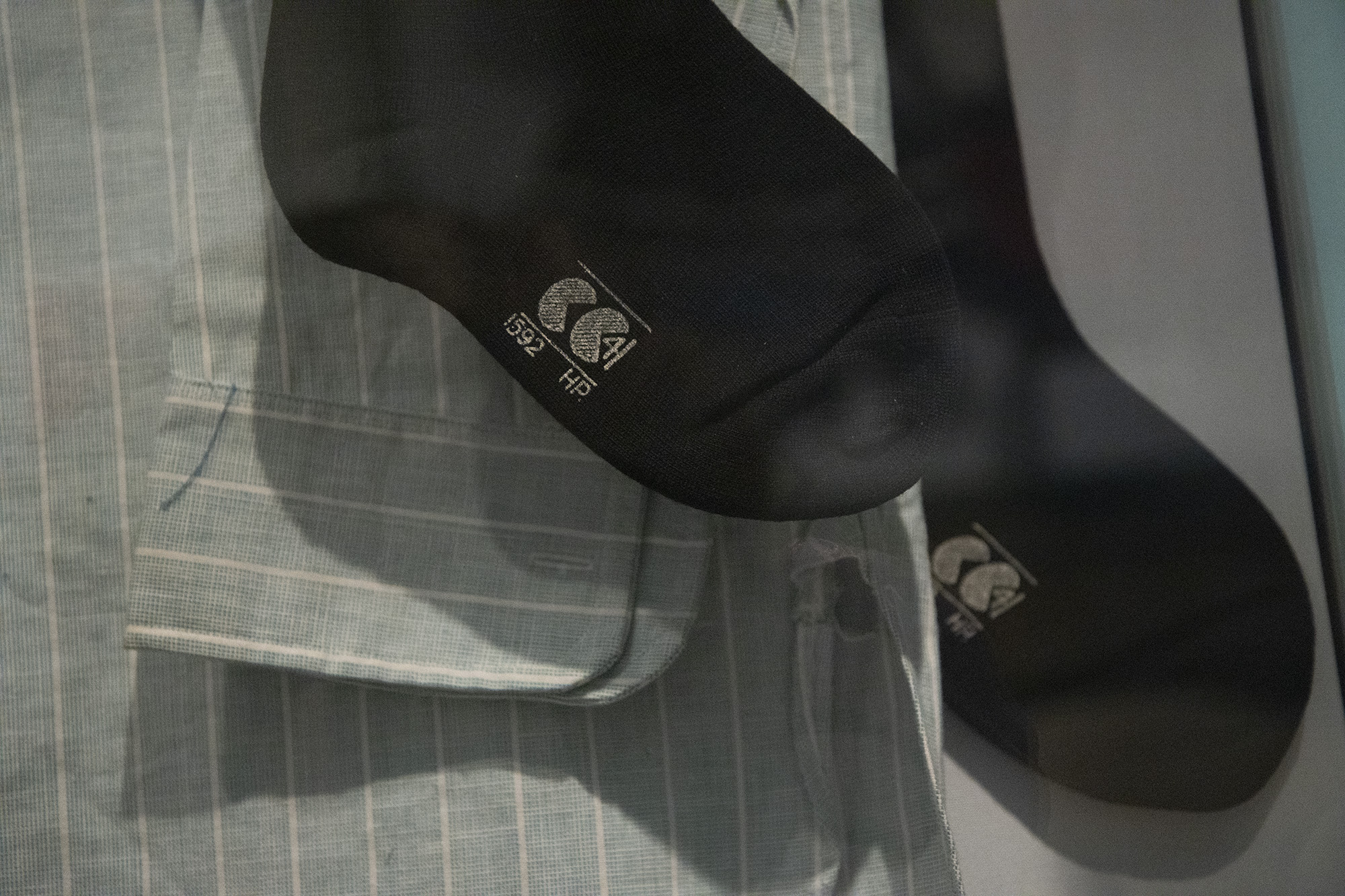 A pair of black socks bearing the "Civilian Clothing" logo, next to a blue and white striped shirt