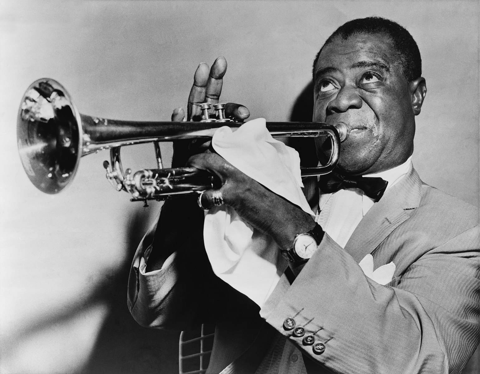 A black and white photograph of Louis Armstrong playing his trumpet