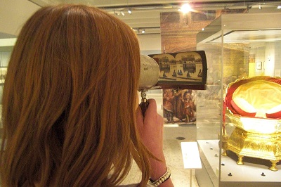 a woman looking closely at a stereoscope (left eye and right eye images next to each other)