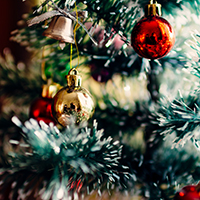Red and gold coloured baubles hanging on an artificial Christmas tree
