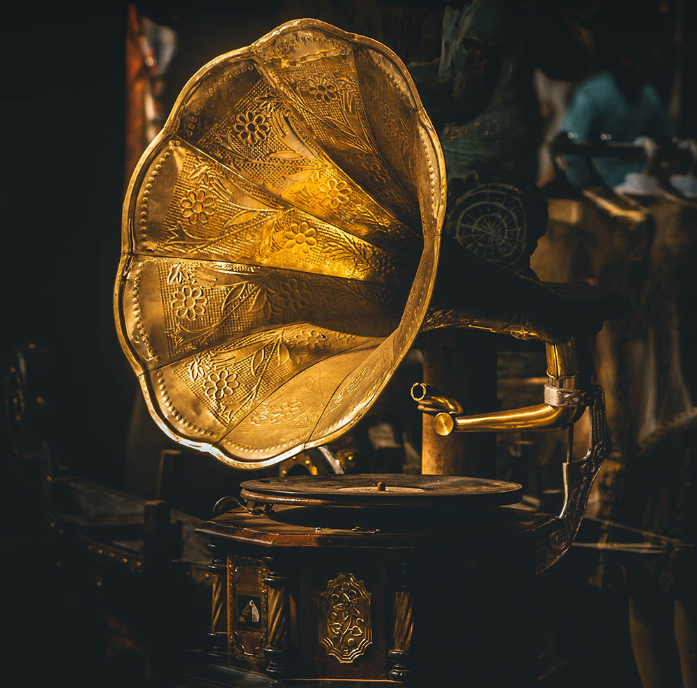 A photograph of a gramophone record player with a floral design on the trumpet