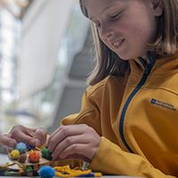 A girl crafting with mini pom poms in the Herbert's covered court