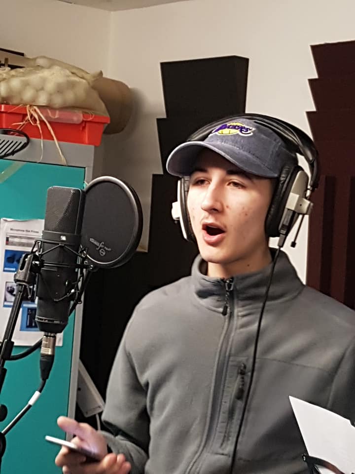 young man singing into a studio microphone