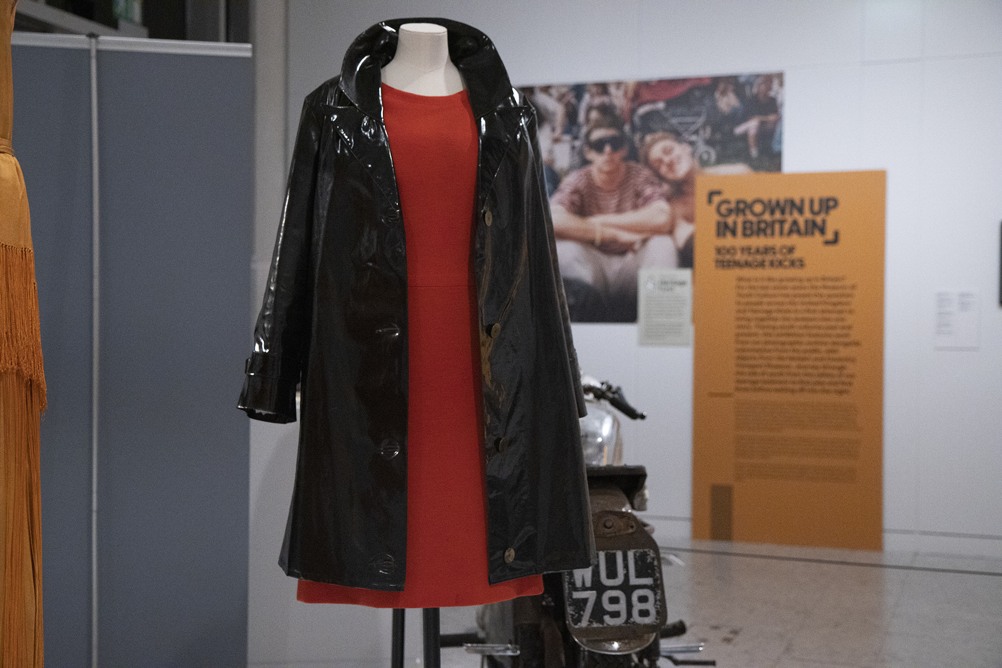 A red mini dress with a black patent mac on display in Grown Up in Britain