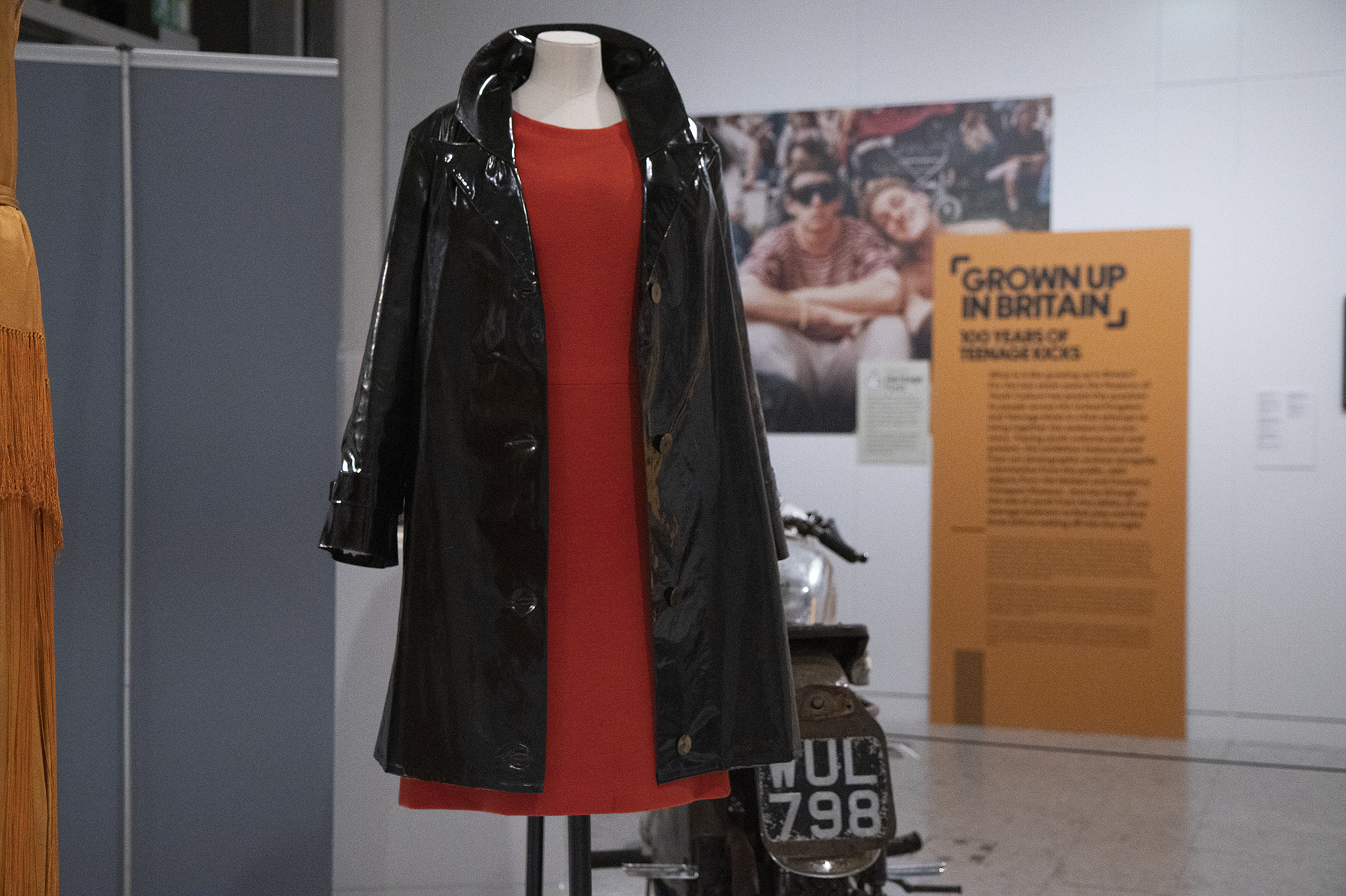 A red mini dress with a black patent mac on display in Grown Up in Britain