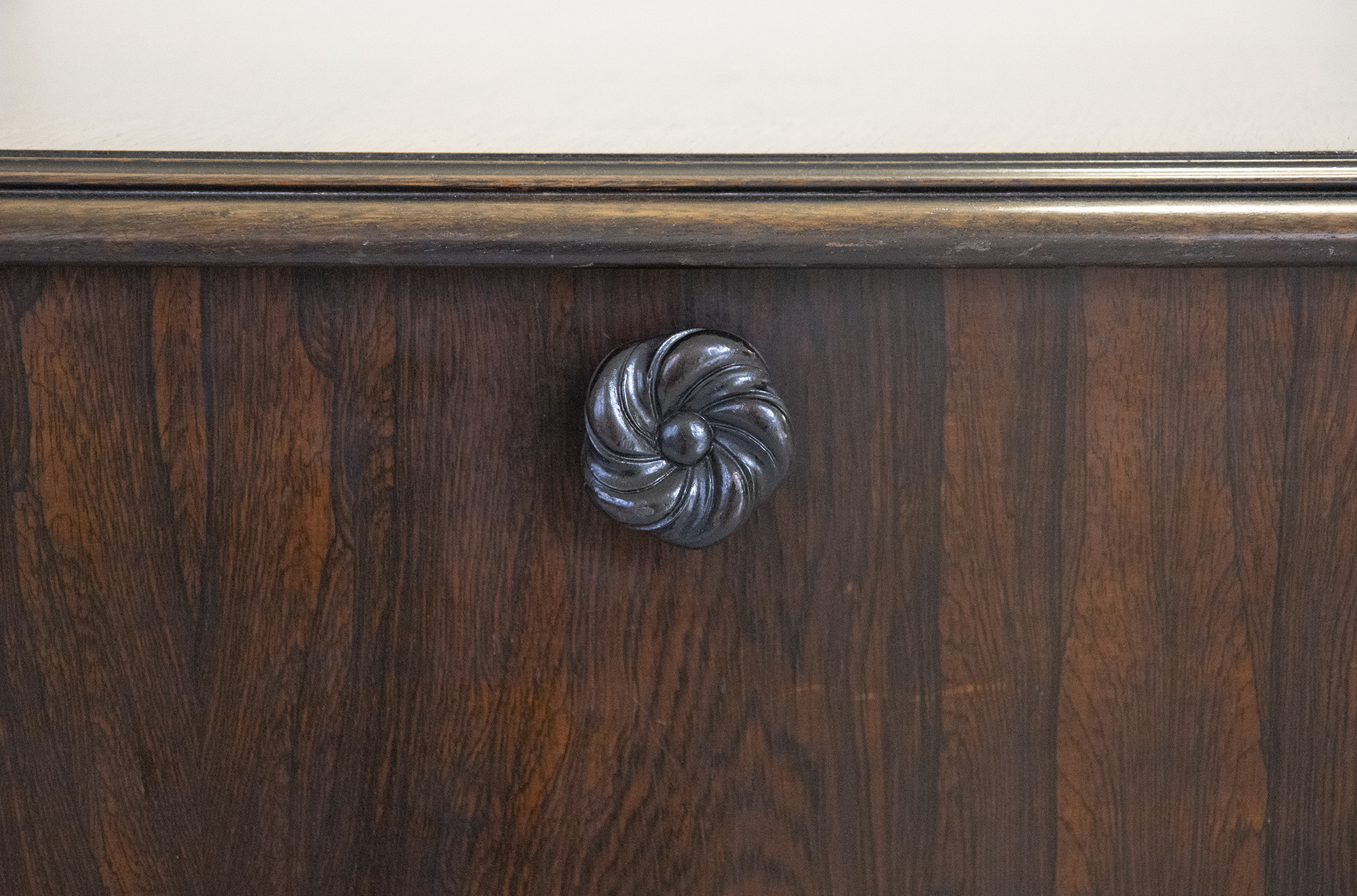 Close up of a flower-shaped wooden knob on the side of the piano