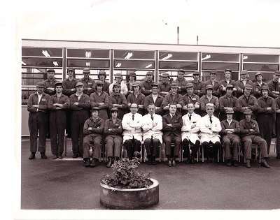 a black and white group photo of men in overalls 