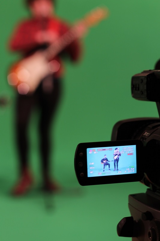 guitarist against green screen being filmed